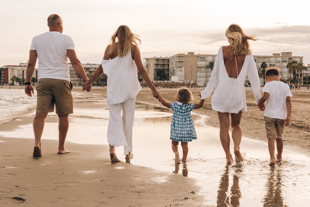 Une famille marche ensemble, main dans la main, à contre-jour.