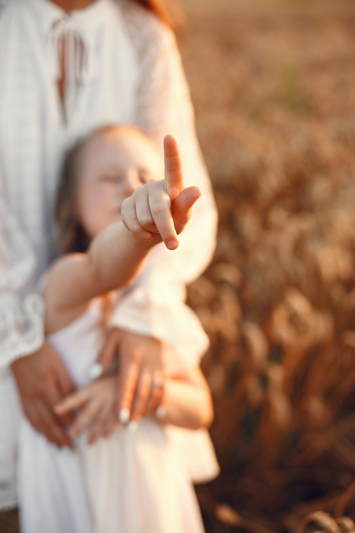 Deux mains d'adulte entourent celles d'un enfant, lumière douce.